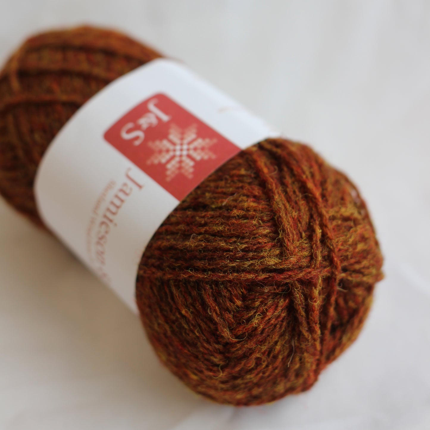 Ball of brown yarn with a label on a white background