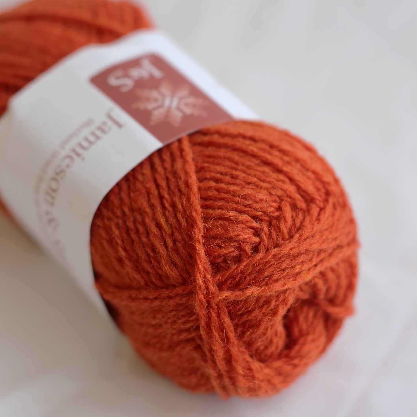Ball of orange yarn with a label on a white background