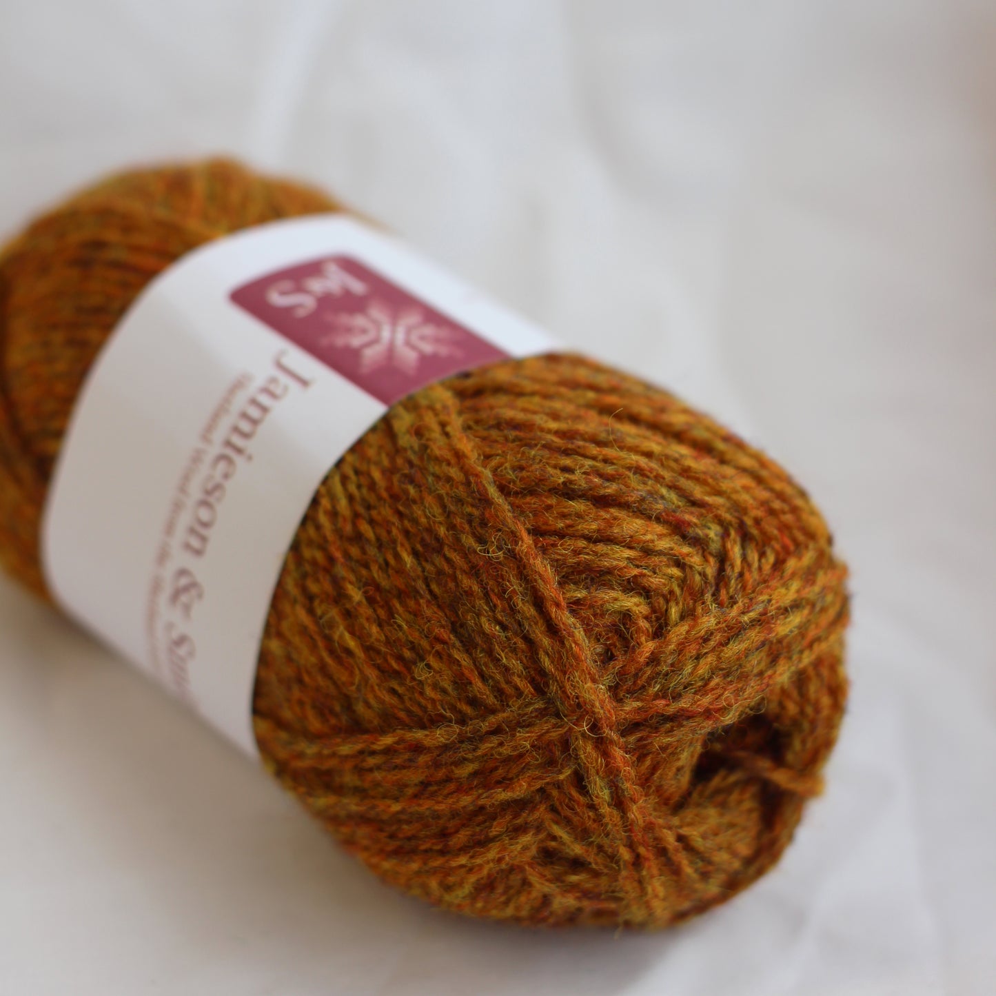 Ball of brown yarn with a label on a white background