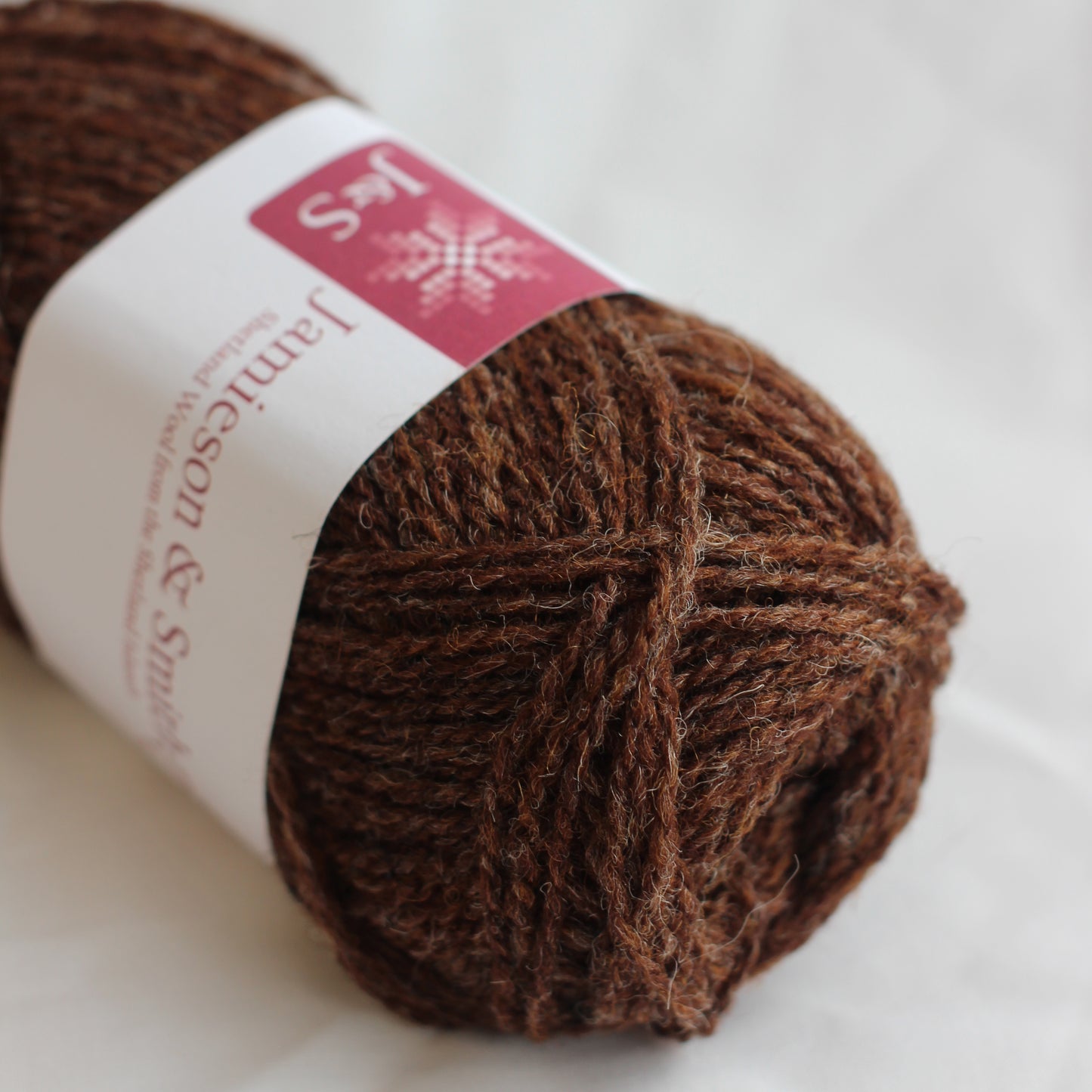 Ball of brown yarn with a label on a white background