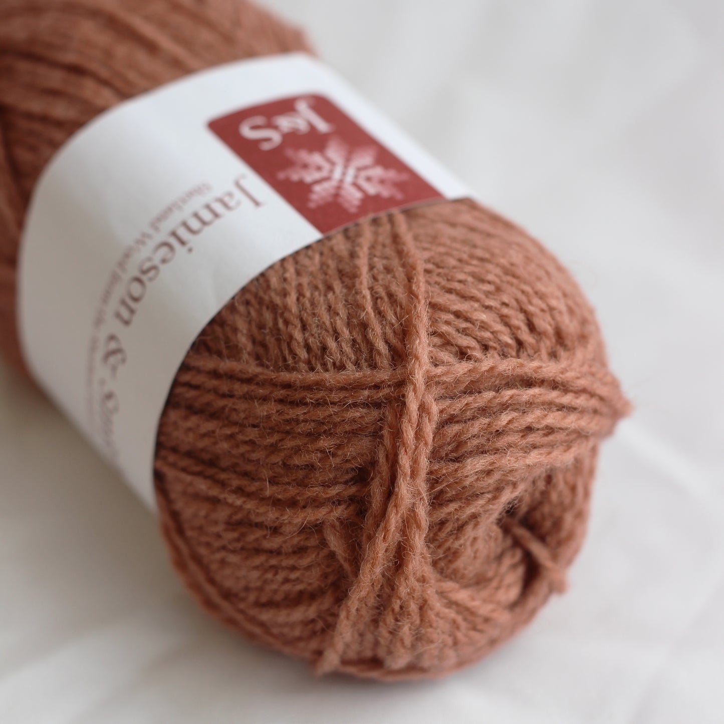 Ball of brown yarn with a label on a white background
