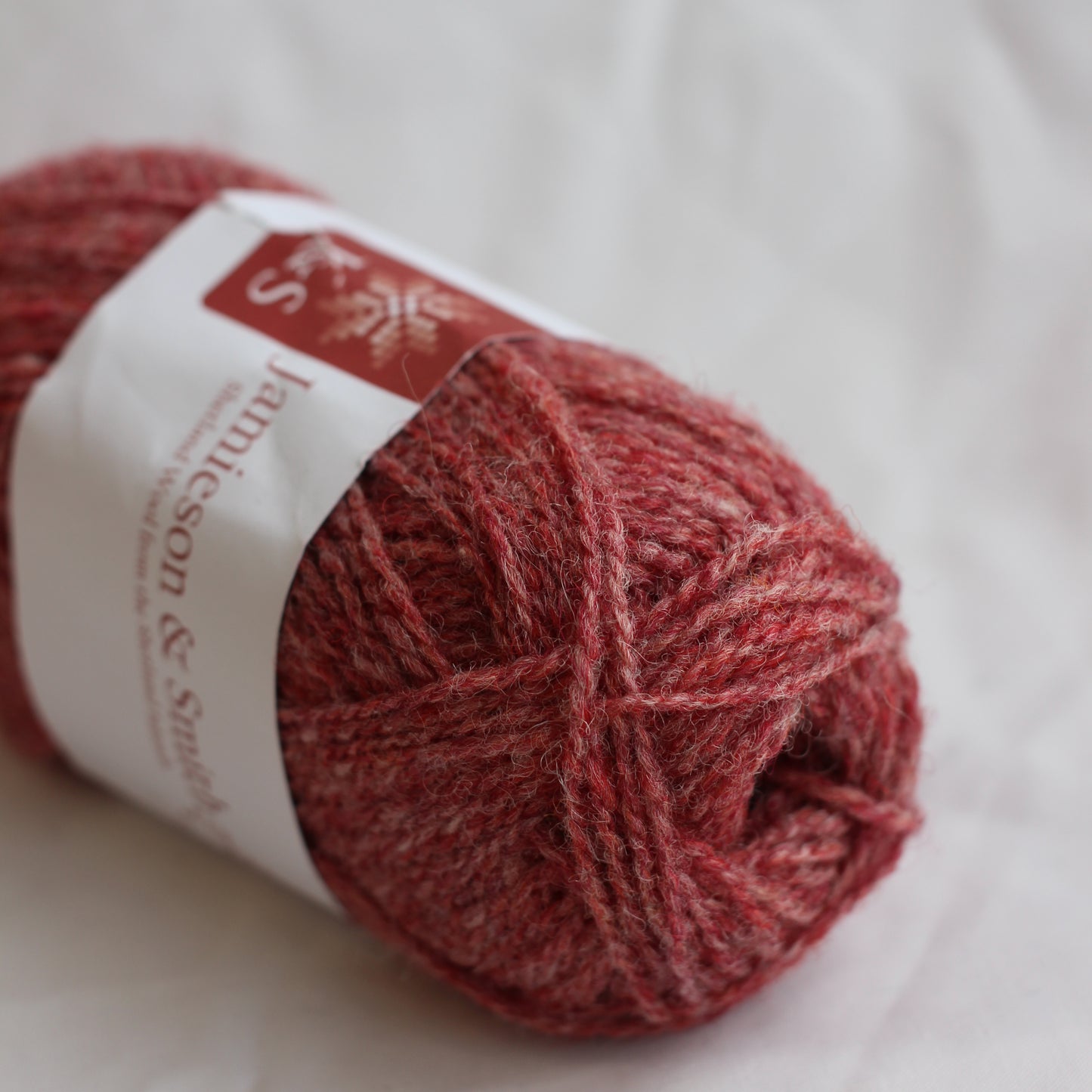 Red skein of yarn with a label on a white background