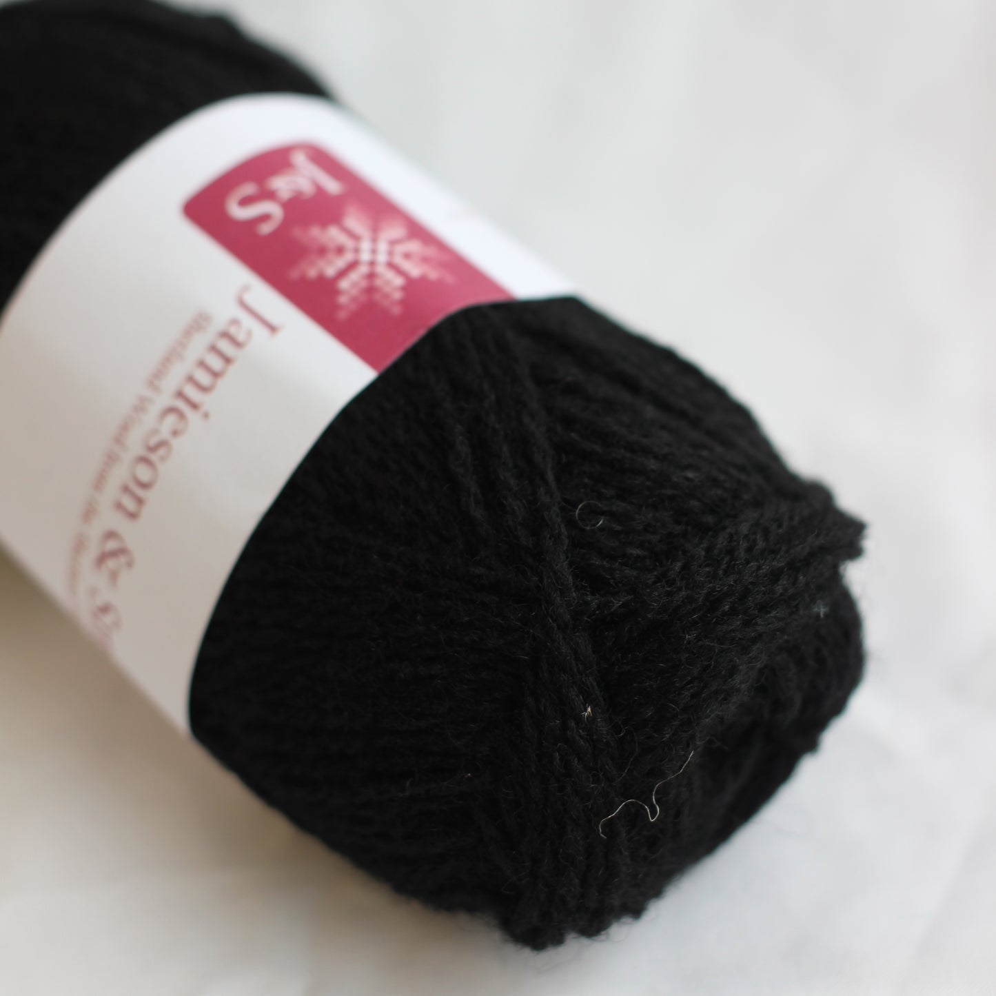 Black yarn ball with a label on a white background