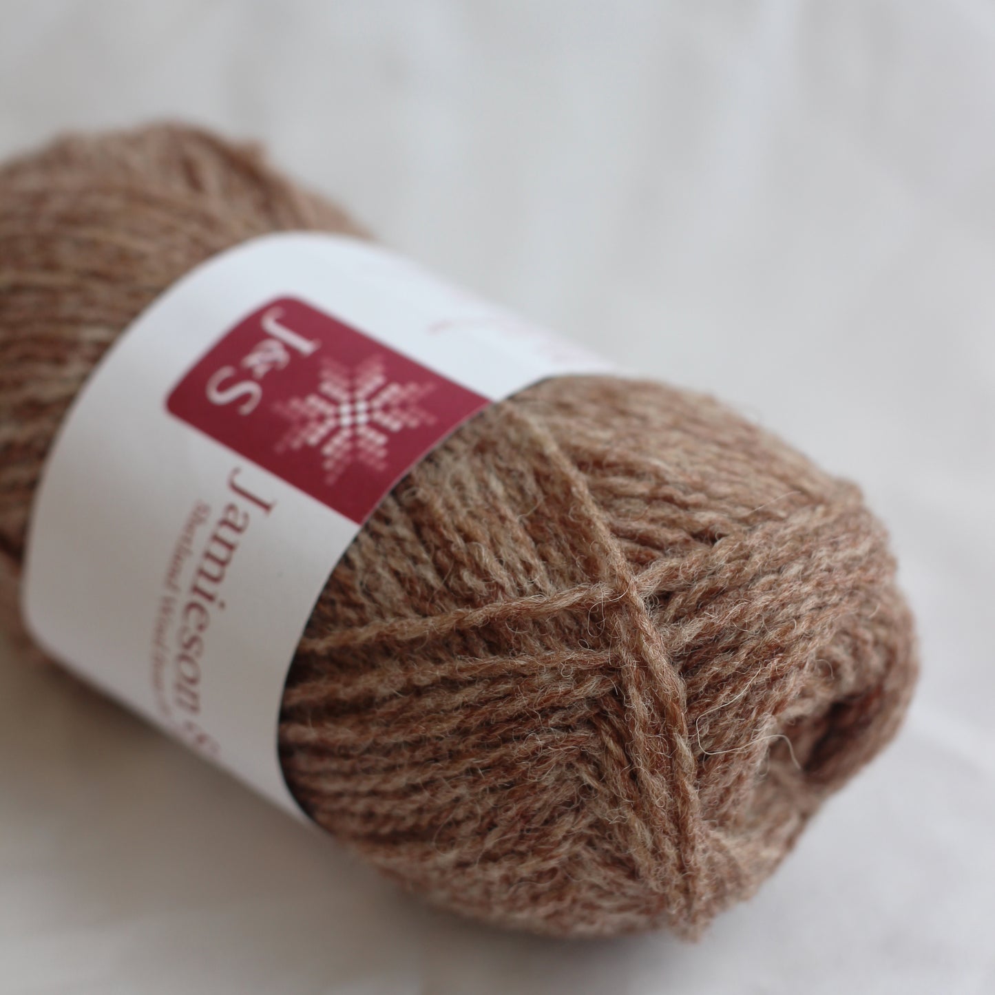 Ball of brown yarn with a label on a light background