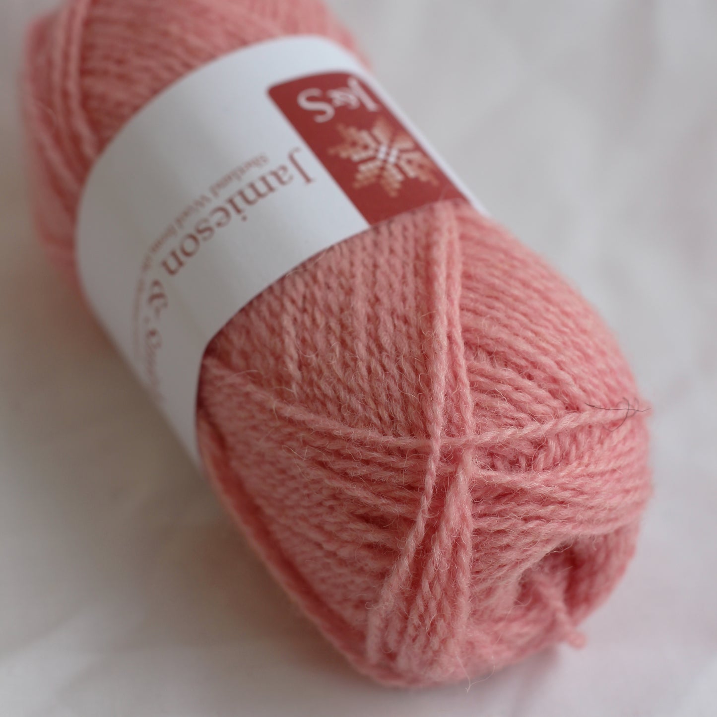 Ball of pink yarn with a label on a white background