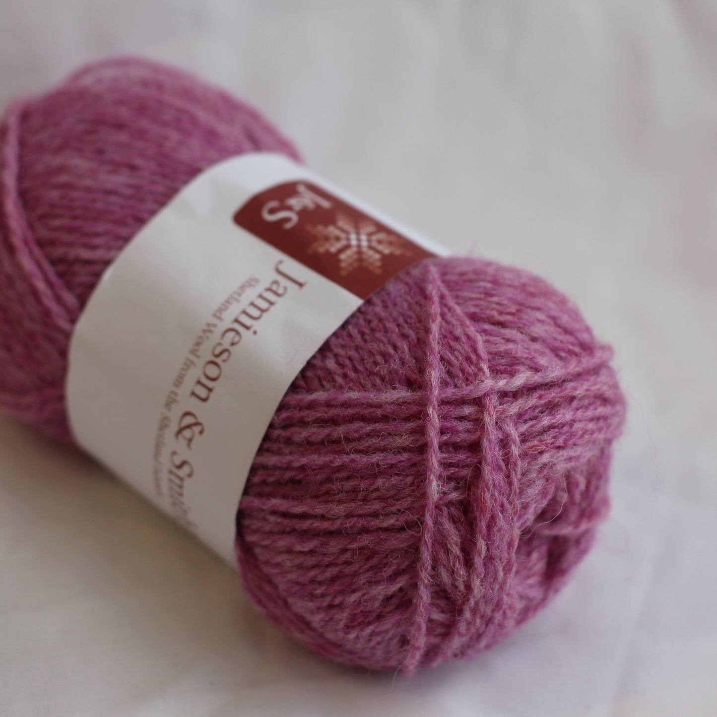 Ball of pink yarn with a label on a white background