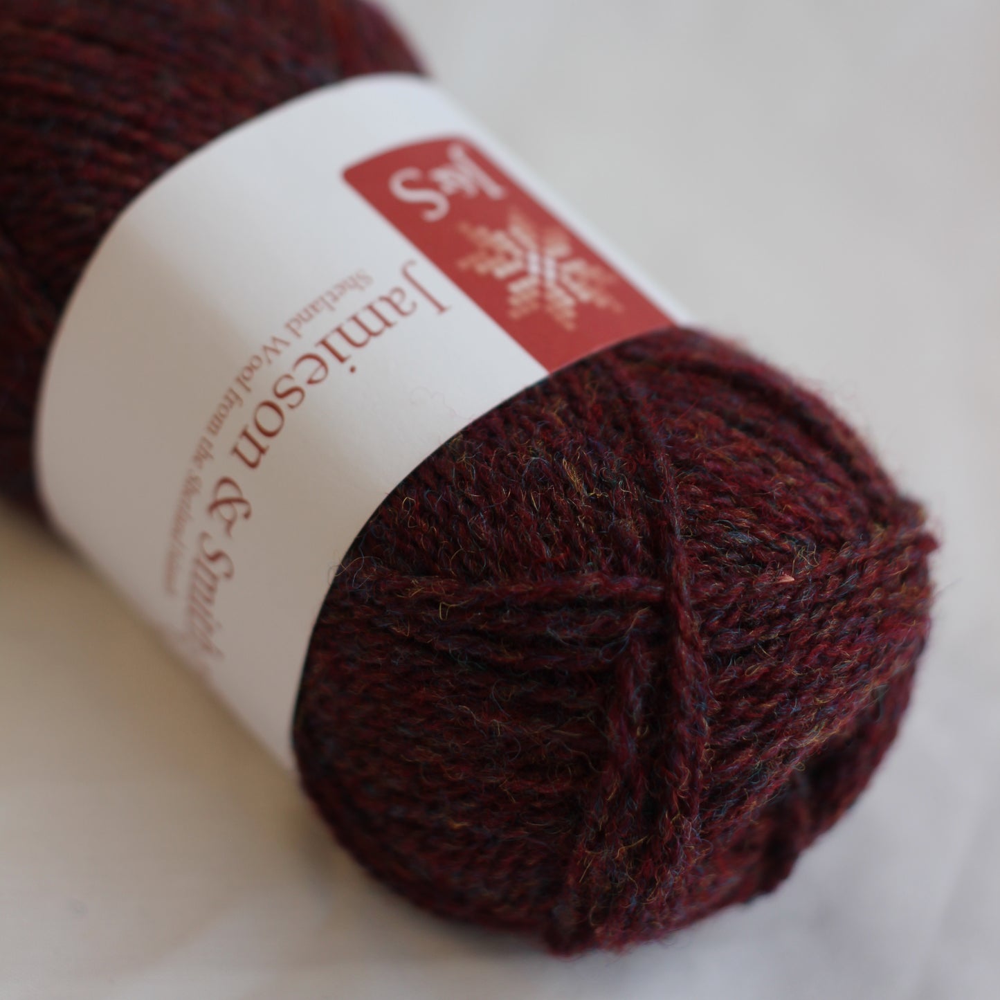 Ball of dark red yarn with a label on a light background