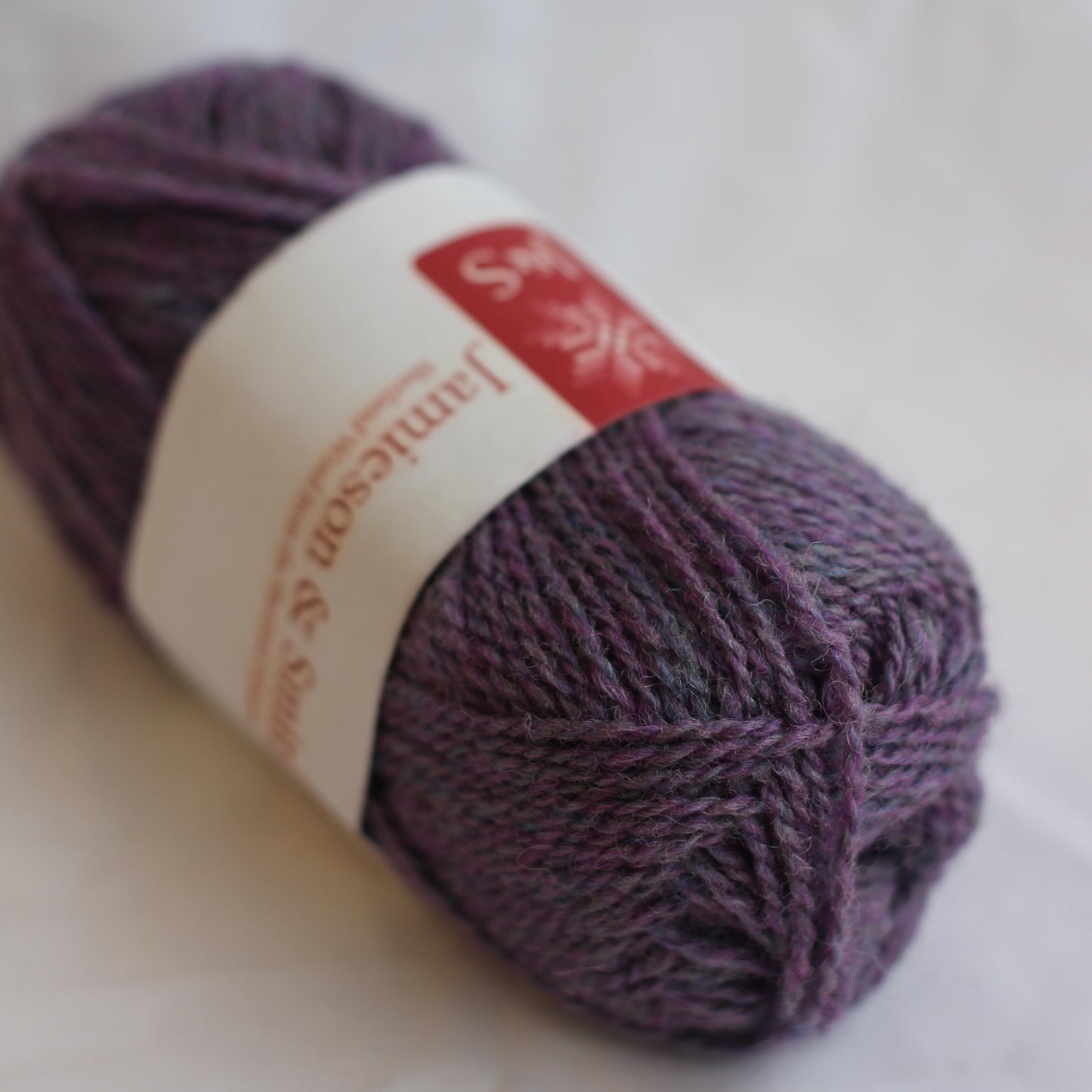 Ball of purple yarn with a label on a white background